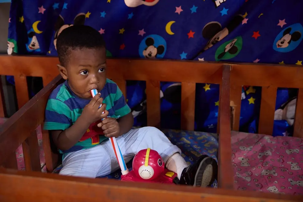 A toddler standing at a cot in the daycare room