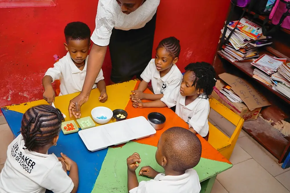 A member of nursery staff helping toddlers at snack time