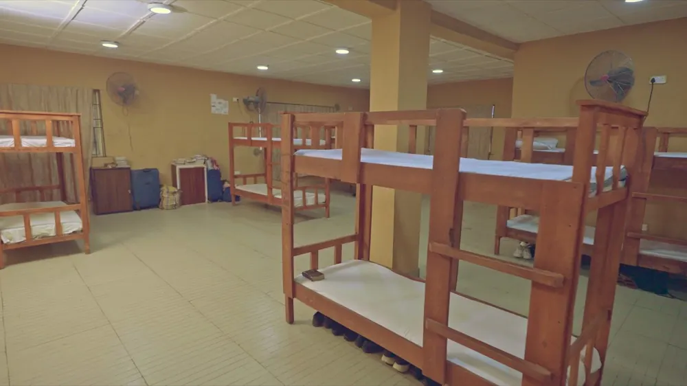 A Life Baker boarding dormitory with wooden bunk beds, tiled floors and ceiling fans